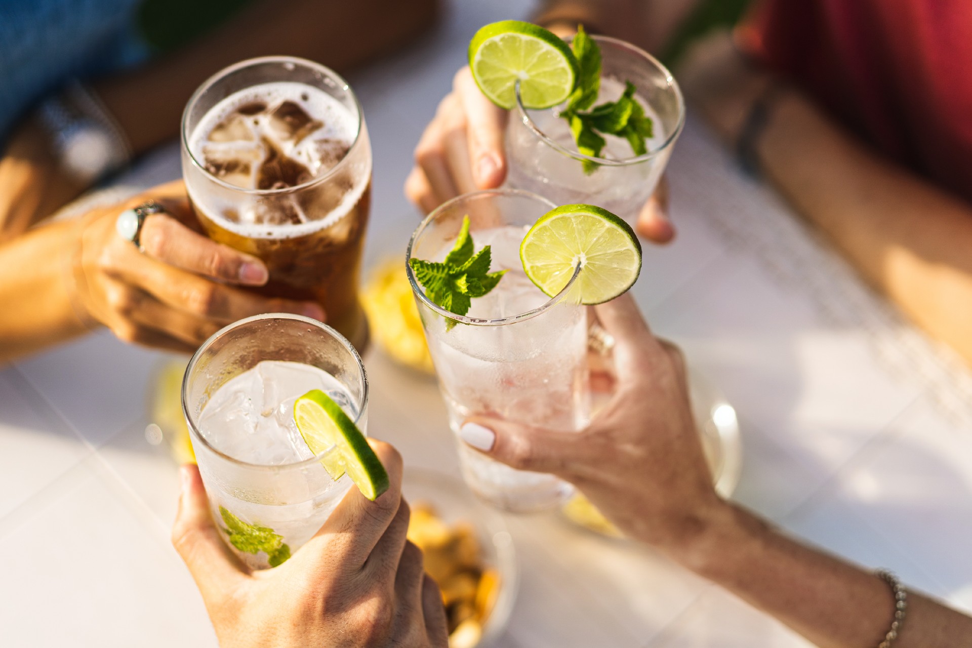 Group of people celebrating toasting with cocktails - cropped detail with focus on hands - lifestyle concept of drinks and alcohol